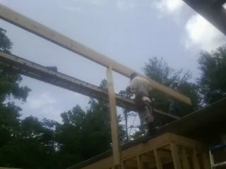 Carpenter setting a ridge beam over a new addition frame — Ice Dam Removal by Roofing Brothers in New Hudson