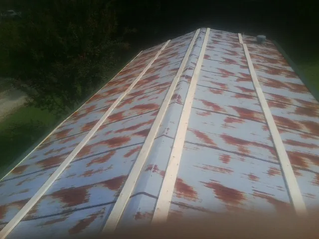Rusted metal roof panels with new wood purlins before replacement — Storm Damage Roof Repair in New Hudson by Roofing Brothers