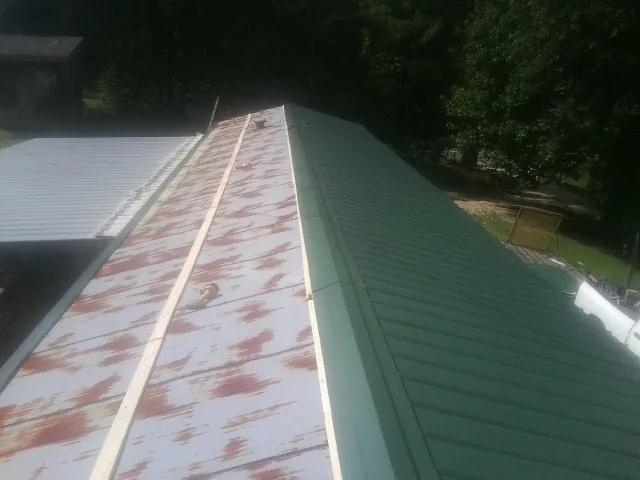 Old rusted panels beside newly installed green metal roofing — Wind Damage Roof Repair by Roofing Brothers in New Hudson