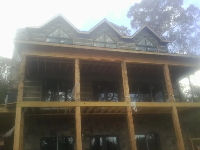 Dormers and porch framing on a large log home under construction — Roof Coating work by our crew in New Hudson