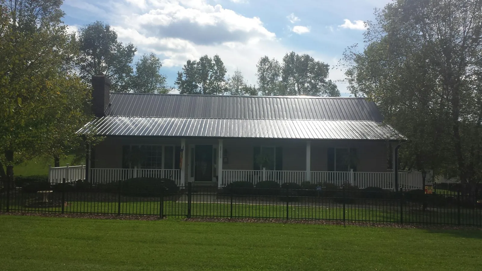 Gray metal roof on a brick ranch with a full width front porch — Gutter Guard Installation work by our crew in New Hudson