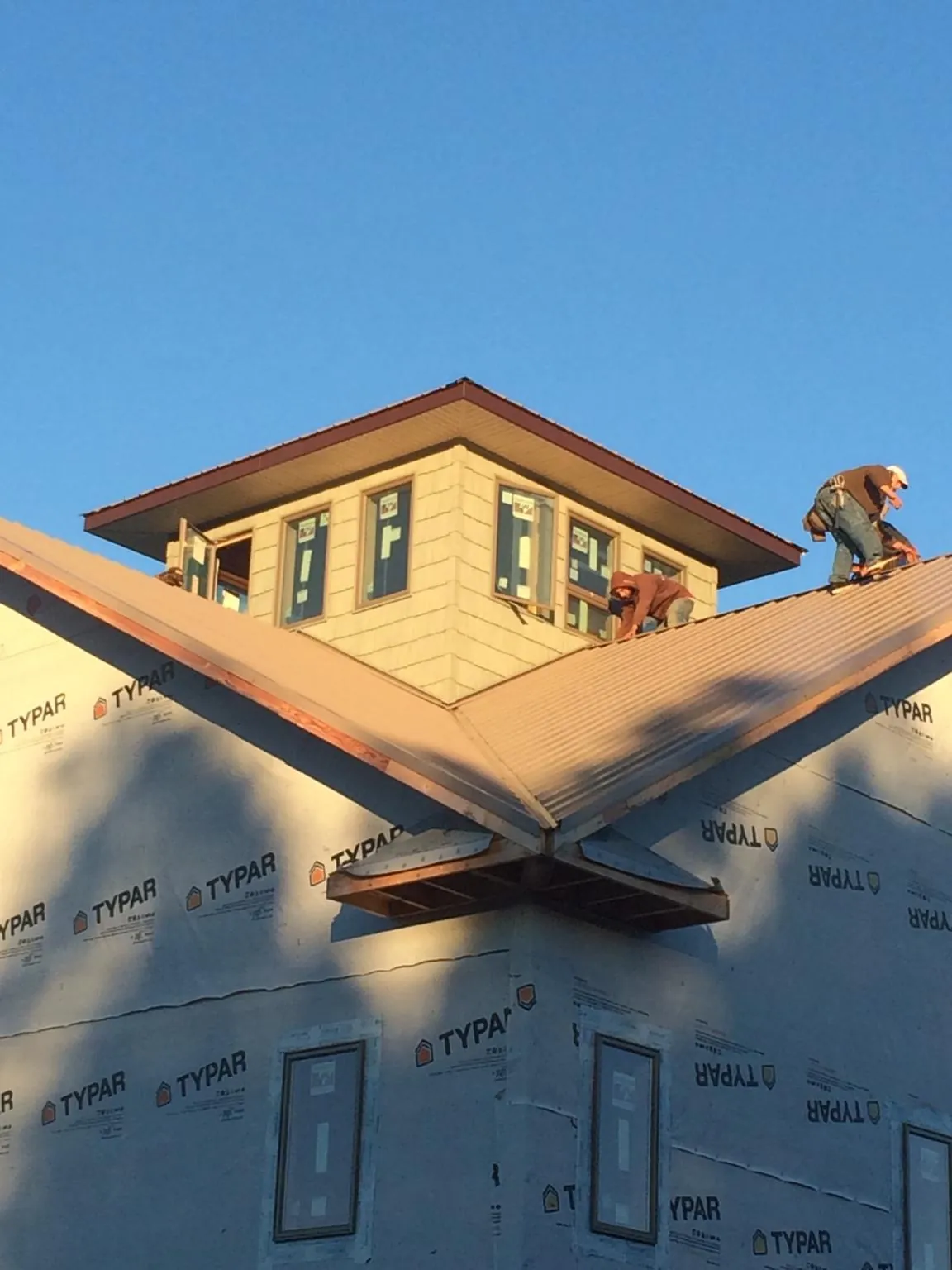 Roofers working around a rooftop cupola on a new metal roof at sunset — Roof Waterproofing in New Hudson by Roofing Brothers